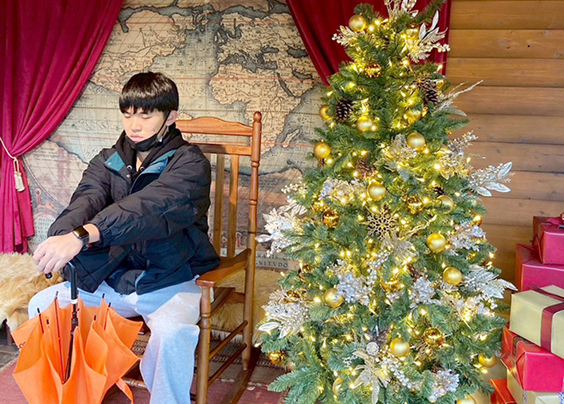 クリスマスツリーと写る佐藤さん